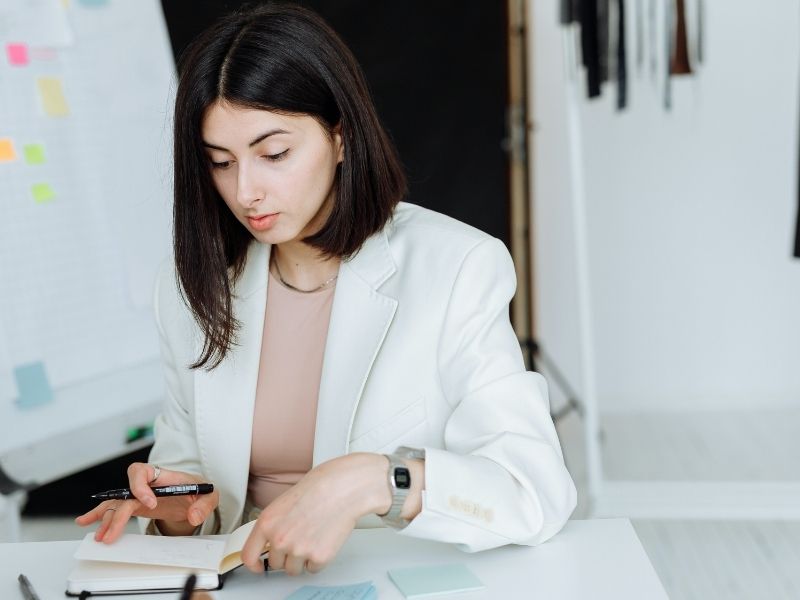 Woman in White Blazer Writing on White Notebook